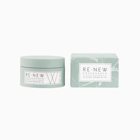 Zielony pojemnik z kremem do stylizacji włosów RE-NEW Copenhagen, Styling Cream nr 02, obok opakowania z marmurkowym wzorem, na białym tle.