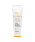 Zdjęcie produktu przedstawiające odżywkę do włosów milk_shake z linii "make my day" w tubie o pojemności 250 ml. Opakowanie jest białe z pomarańczowym logo marki i grafiką bitej śmietany w centralnej części. Poniżej znajduje się nazwa serii oraz informacja o zawartości protein mleka ("with milk proteins"). Tuba posiada pomarańczowe zamknięcie typu flip-top i jest przedstawiona na tle szachownicy symbolizującej przezroczystość.